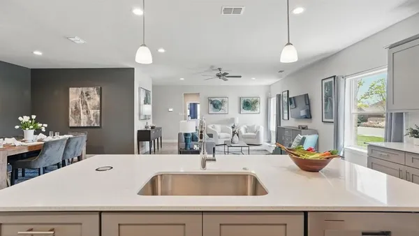 a kitchen with a sink a counter appliances and living room view