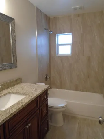 a bathroom with a granite countertop sink toilet and shower
