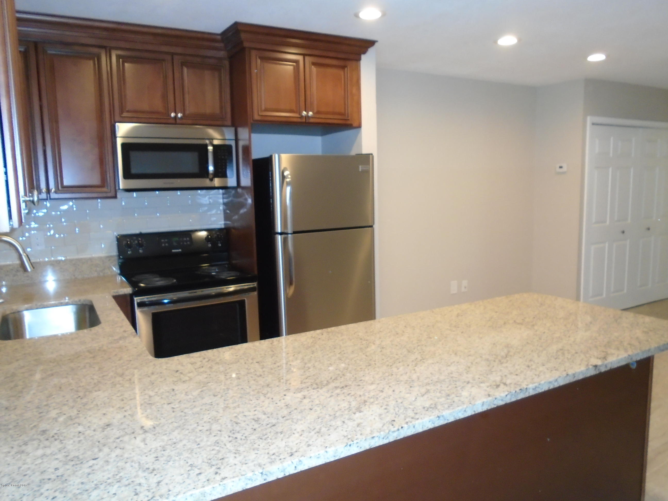 5600 North Banana River Boulevard, Unit 46 Cocoa Beach, FL 32931 - Photo 3 of 13 a kitchen with granite countertop a refrigerator stove and microwave