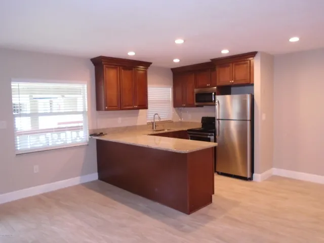a kitchen with stainless steel appliances granite countertop a refrigerator and a stove top oven