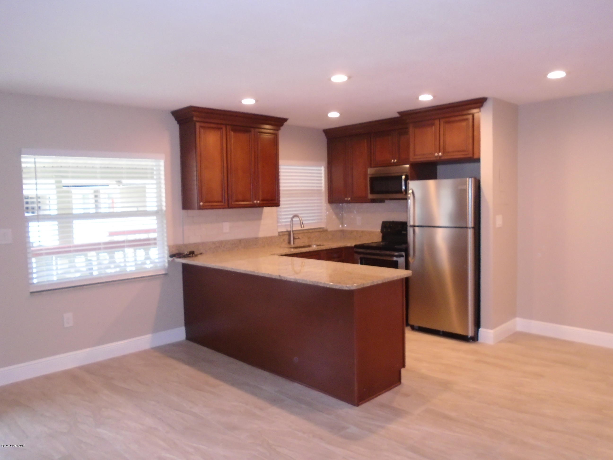 5600 North Banana River Boulevard, Unit 46 Cocoa Beach, FL 32931 - Photo 4 of 13 a kitchen with stainless steel appliances granite countertop a refrigerator and a stove top oven
