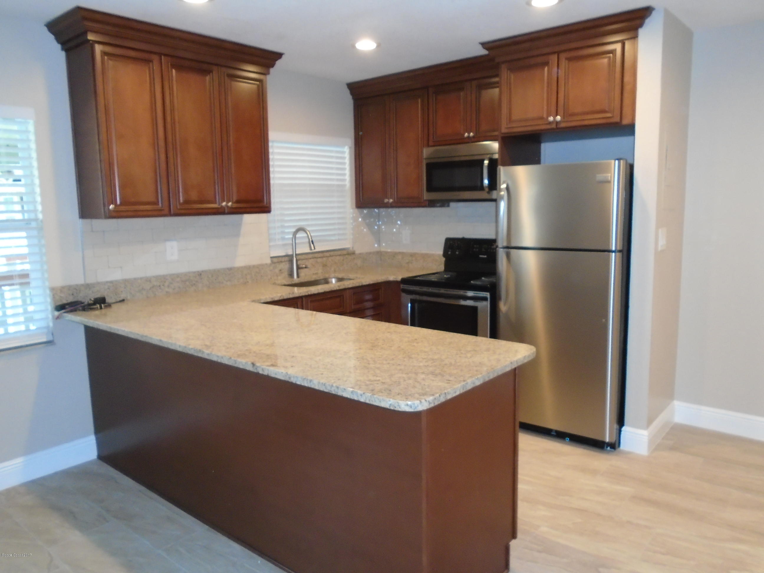 5600 North Banana River Boulevard, Unit 46 Cocoa Beach, FL 32931 - Photo 5 of 13 a kitchen with a refrigerator a sink and cabinets