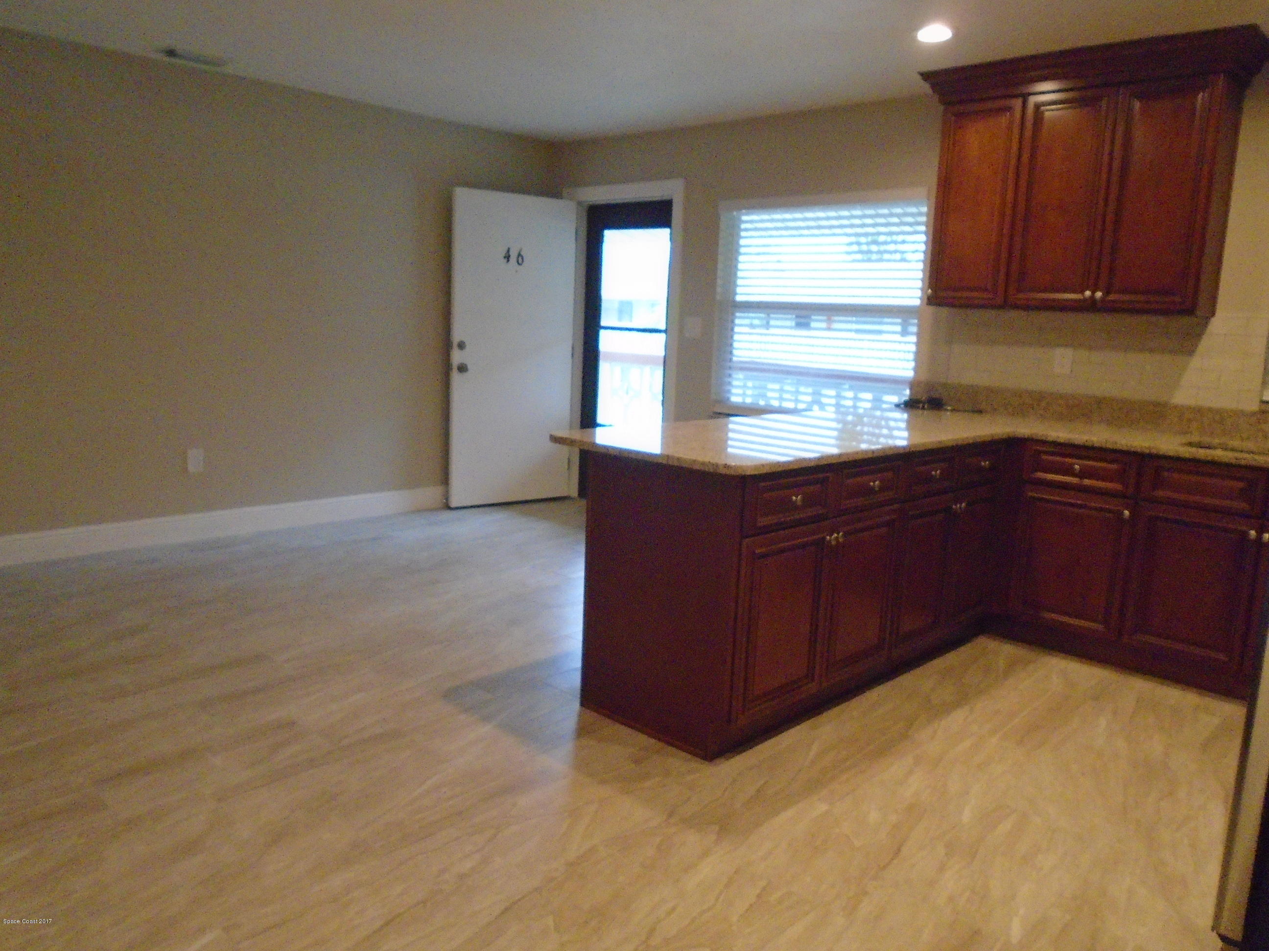 5600 North Banana River Boulevard, Unit 46 Cocoa Beach, FL 32931 - Photo 7 of 13 a kitchen with stainless steel appliances granite countertop a sink and cabinets with wooden floor