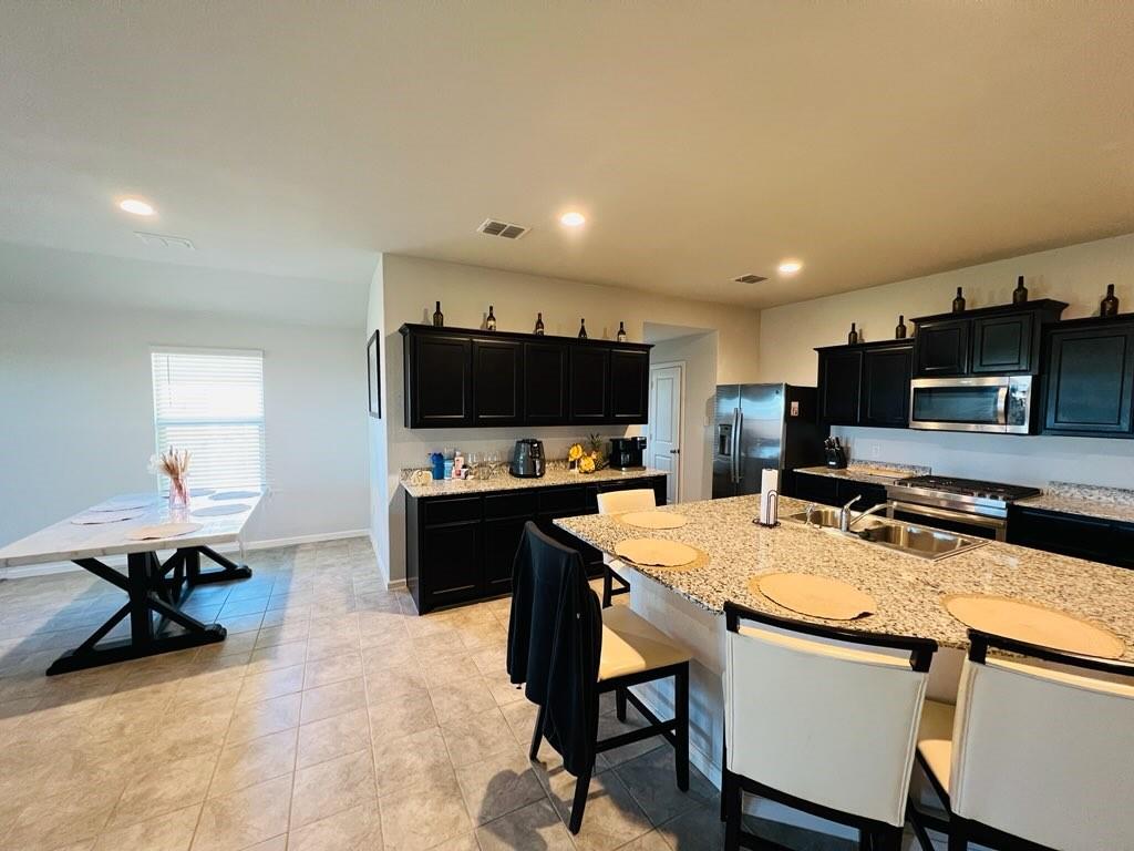 a kitchen with stainless steel appliances a stove a sink a microwave a dining table and chairs