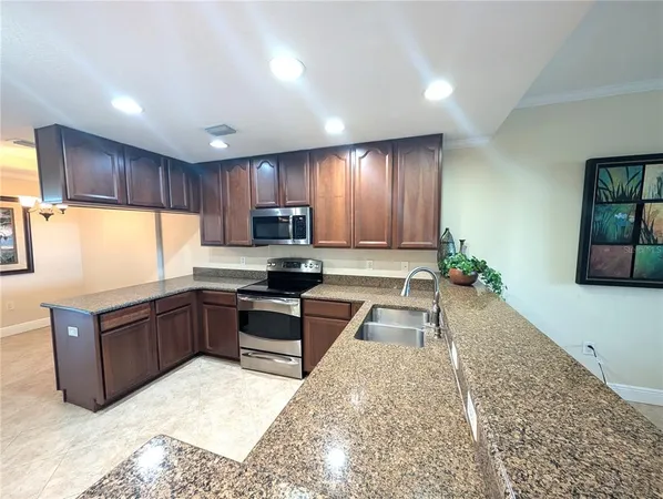 a large kitchen with kitchen island granite countertop a stove refrigerator sink and cabinets