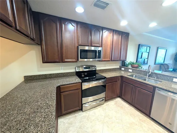 a kitchen with granite countertop wooden cabinets and stainless steel appliances