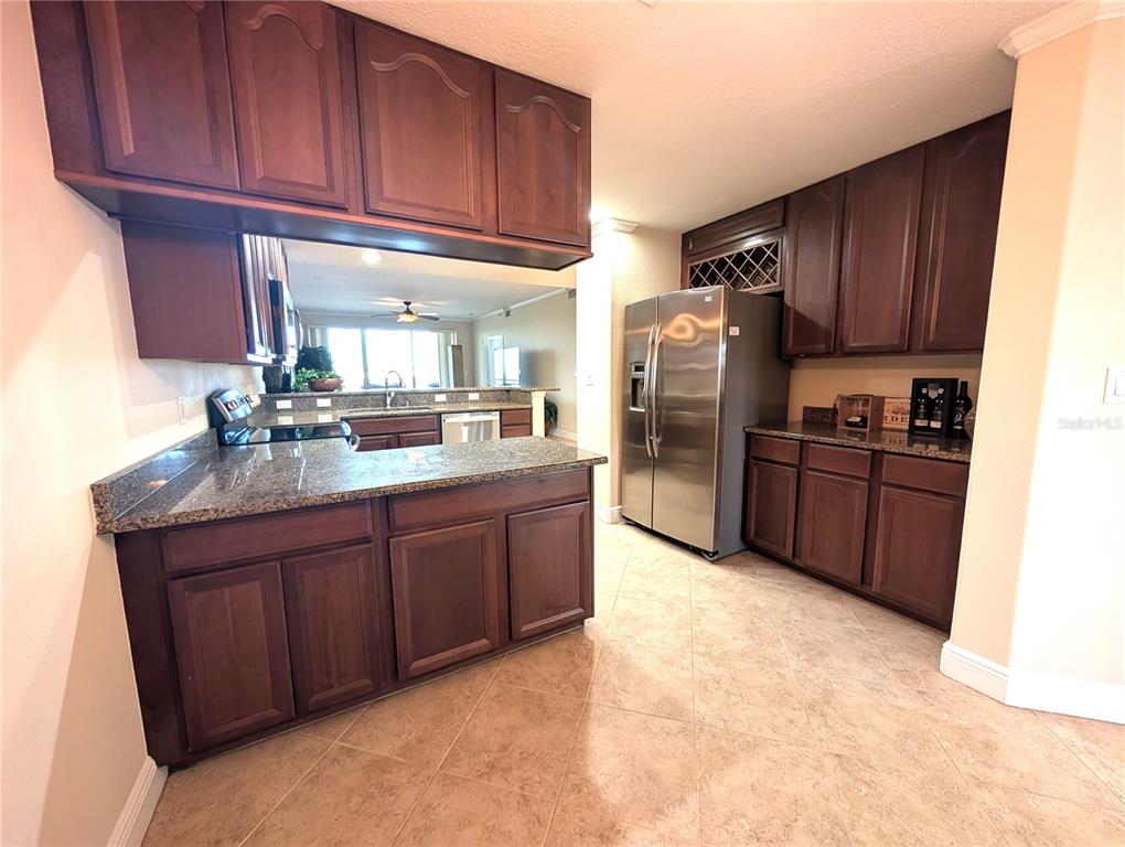 7070 Key Haven Road, Unit 602 Seminole, FL 33777 - Photo 22 of 48 a kitchen with stainless steel appliances granite countertop a refrigerator a sink dishwasher and wooden cabinets with wooden floor