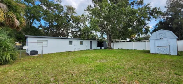 a backyard of a house with plants and large tree