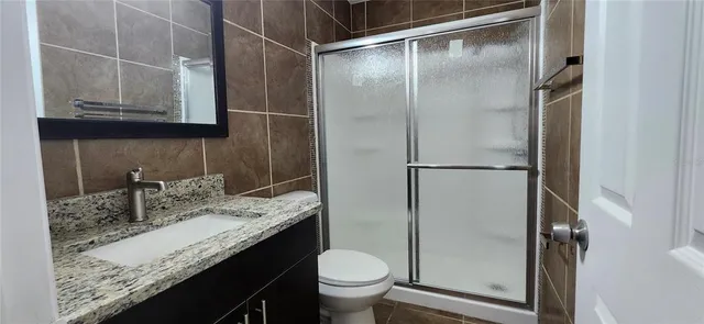 a bathroom with a granite countertop sink toilet and shower