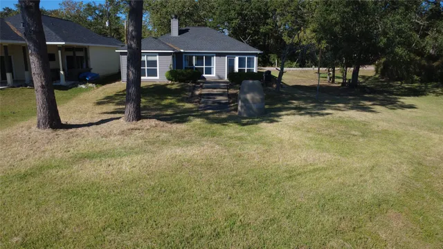 a front view of a house with a yard covered with snow and trees
