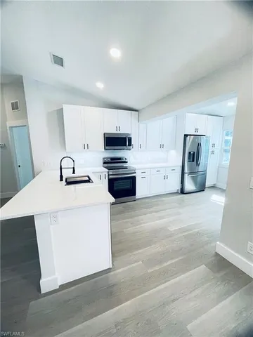 a view of kitchen with stainless steel appliances granite countertop cabinets and wooden floor
