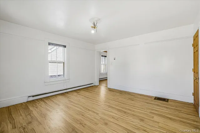 an empty room with wooden floor cabinet and windows