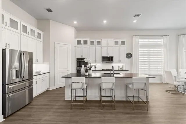 a kitchen with stainless steel appliances kitchen island granite countertop a dining table chairs refrigerator and sink