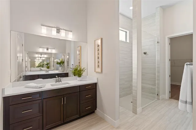 a bathroom with a double vanity sink a large mirror a shower and