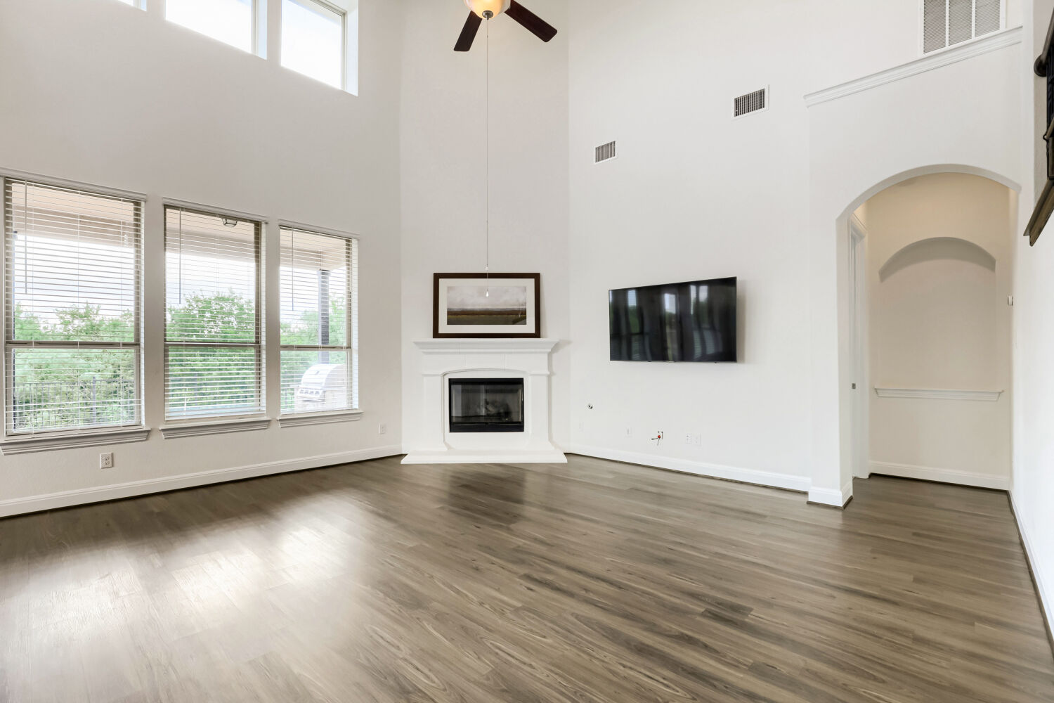 19205 Burrowbridge Road Pflugerville, TX 78660 - Photo 10 of 38 A spacious living room features soaring ceilings and elegant flooring, with a cozy fireplace at its heart.