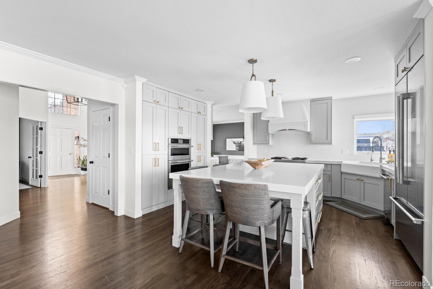 8855 South Wild Iris Run Highlands Ranch, CO 80126 - Photo 15 of 48 a kitchen with stainless steel appliances kitchen island granite countertop a dining table chairs and white cabinets