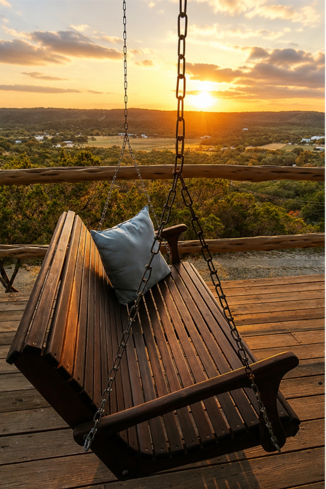 Perched on a wooden deck, a charming porch swing offers sweeping views of the valley at sunset.