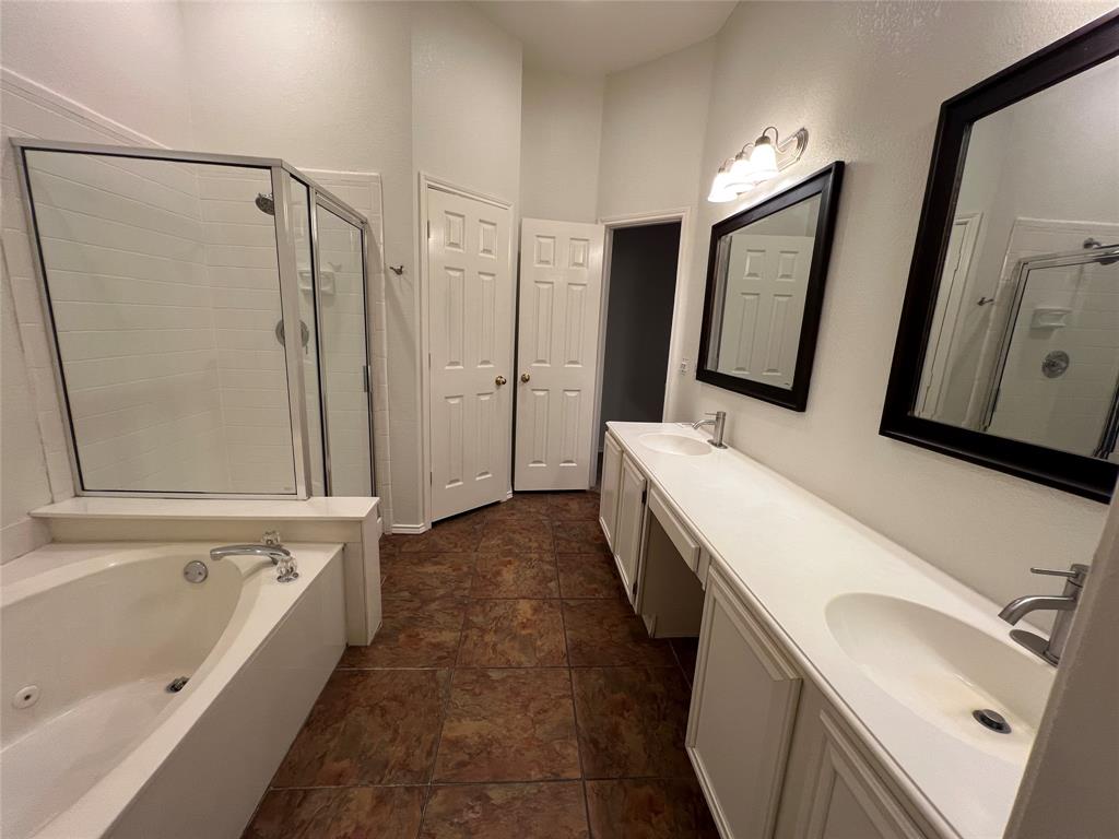 334 Touchdown Drive Irving, TX 75063 - Photo 24 of 32 Spacious bathroom featuring a dual vanity with integrated sinks, a separate walk-in shower with glass enclosure, a built-in bathtub with chrome fixtures, and rich brown tile flooring