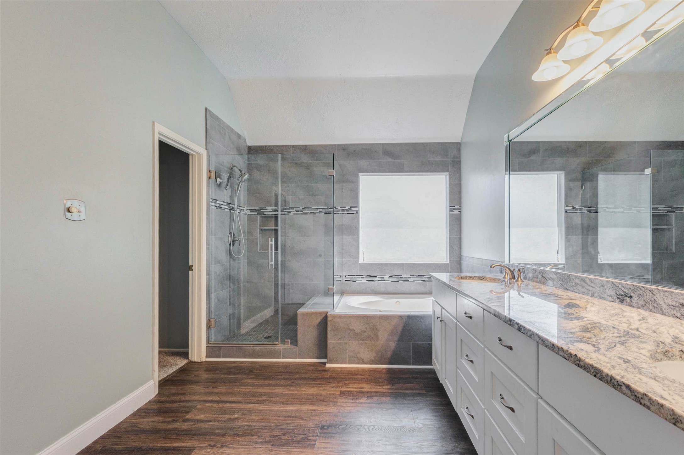 9215 Landry Boulevard Spring, TX 77379 - Photo 27 of 42 The beautifully updated primary bathroom showcases granite countertops, a relaxing soaking tub, and a spacious walk in shower.