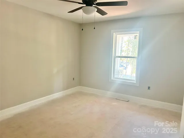 an empty room with a window and a fan