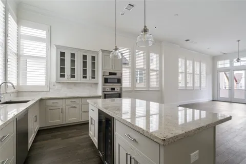 a large kitchen with stainless steel appliances granite countertop a sink and white cabinets