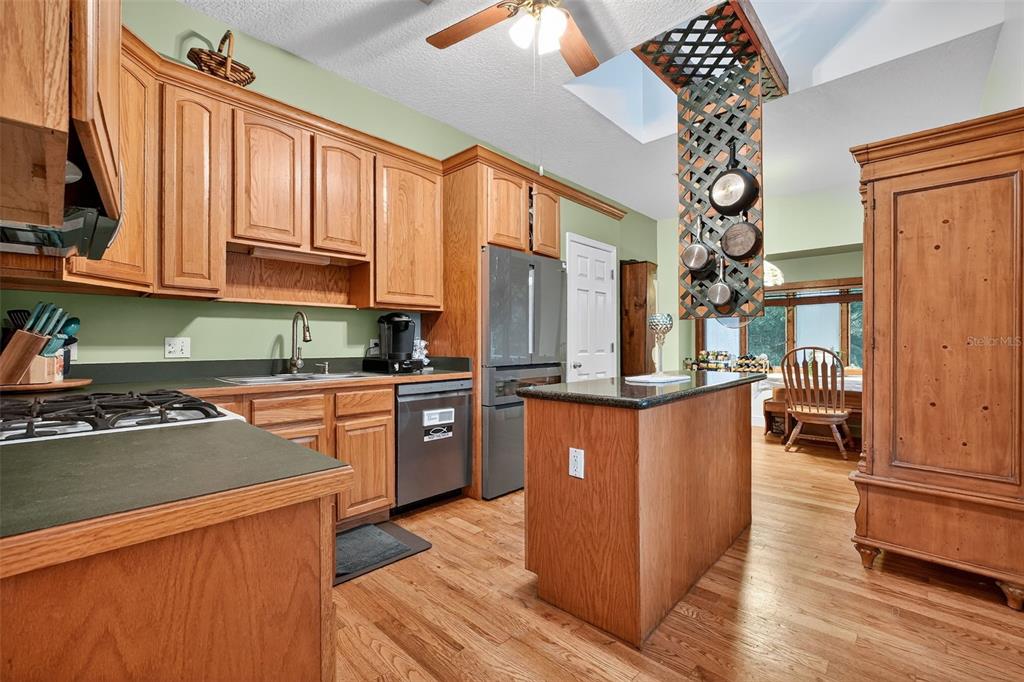 2836 Shenandoah Road DeLand, FL 32720 - Photo 24 of 46 a kitchen with stainless steel appliances granite countertop a refrigerator a sink dishwasher a stove and a dining table with wooden floor
