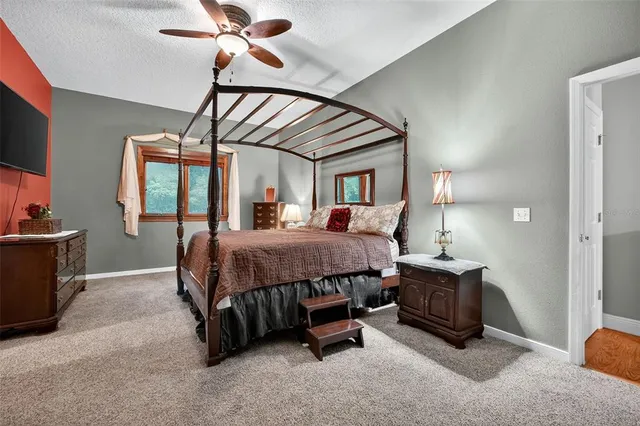 a spacious bedroom with a bed a chandelier and a flat tv screen on dresser