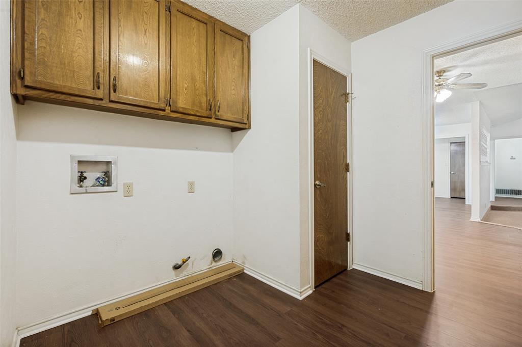 508 South Pedigo Street Pilot Point, TX 76258 - Photo 12 of 26 Dedicated laundry area featuring wood-finish flooring, overhead cabinetry, and white wall finishes