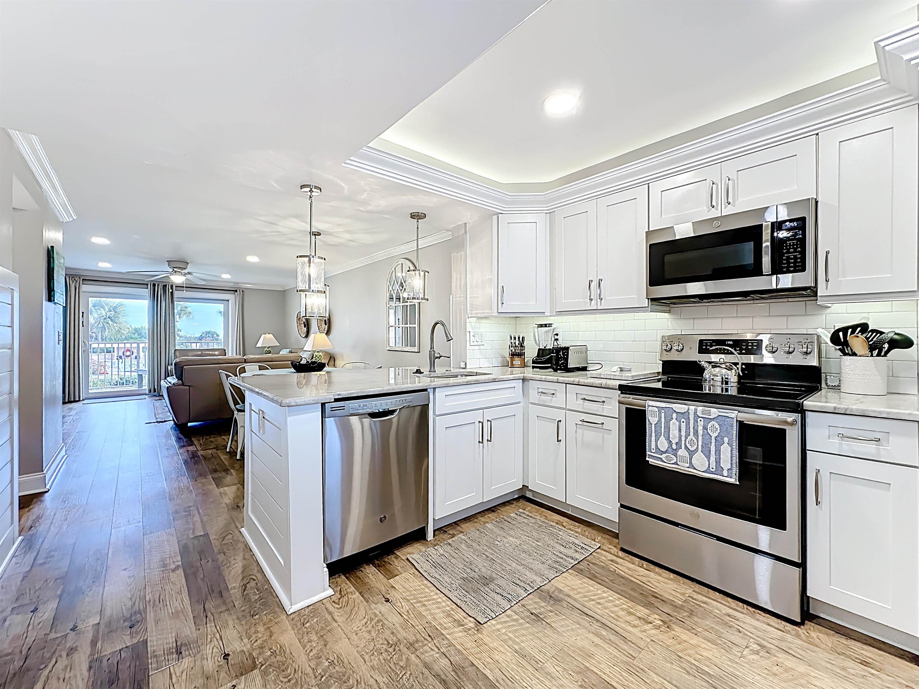 4 Ocean Trace Road, Unit 213 St. Augustine, FL 32080 - Photo 5 of 38 a kitchen with stainless steel appliances white cabinets a sink a stove a microwave and wooden floors