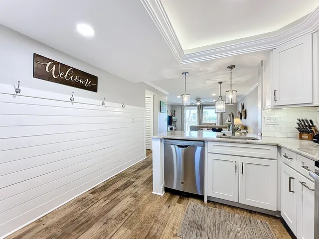 a view of a kitchen with kitchen island granite countertop wooden floor stainless steel appliances and windows