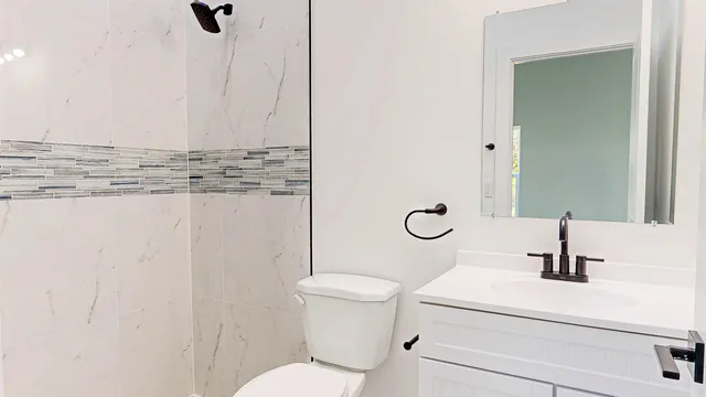 a bathroom with a sink a toilet a mirror and shower
