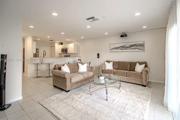 a view of a living room kitchen with stainless steel appliances kitchen island granite countertop a couch and a view of living room