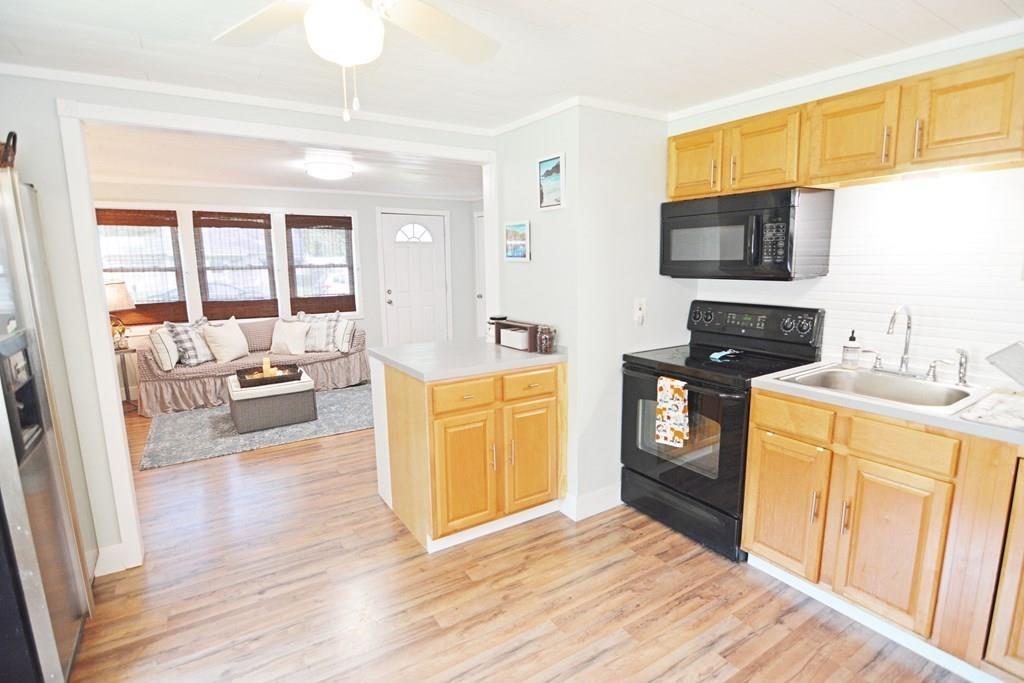 111 Groton Street Springfield, MA 01129 - Photo 6 of 26 a view of a kitchen with a sink dishwasher stove and wooden cabinets with wooden floor