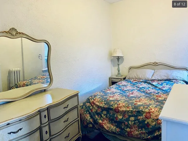a bedroom with a bed and dresser with mirror