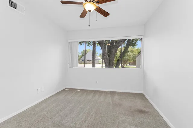 an empty room with a window and a ceiling fan