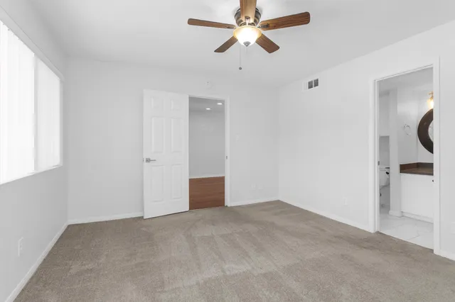 a view of a room with a ceiling fan and carpet