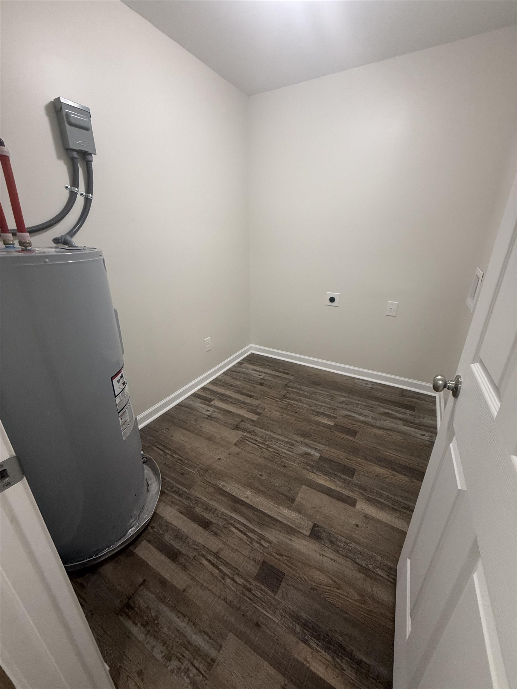 170 Leapwood Road Enville, TN 38332 - Photo 29 of 33 Utility room featuring wood-finish flooring, white baseboards, light-toned walls, and a built-in water heater