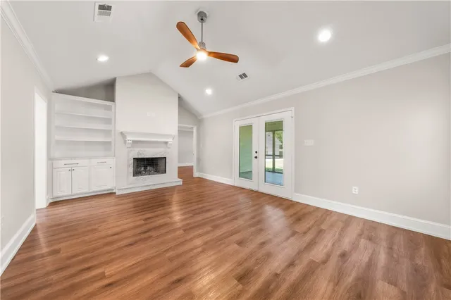 a view of an empty room with wooden floor and a kitchen