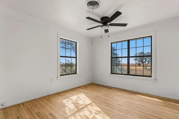 a view of an empty room with window and wooden floor