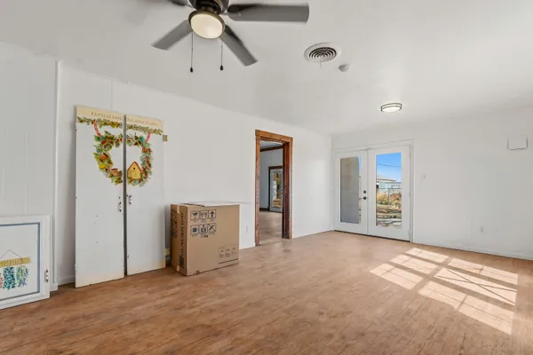 a view of an empty room with a window and kitchen view