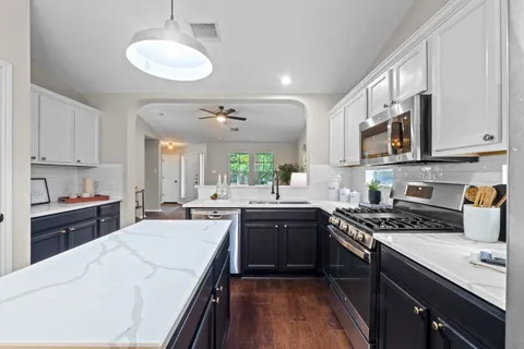 a kitchen with stainless steel appliances granite countertop a sink stove cabinets granite counter tops and a stove