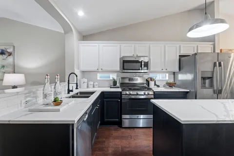a kitchen with stainless steel appliances a sink a stove a refrigerator a center island and cabinets