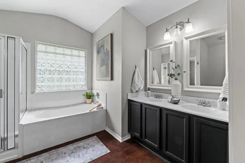 a bathroom with a bathtub a double vanity sink and a mirror