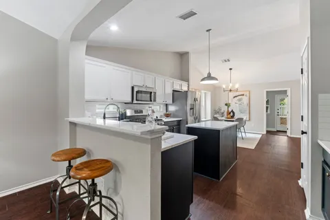 a kitchen with kitchen island granite countertop a sink cabinets and wooden floor