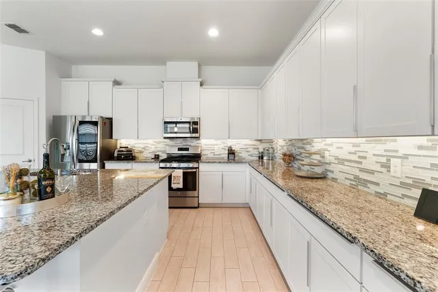 a large kitchen with granite countertop a sink counter top space appliances and cabinets