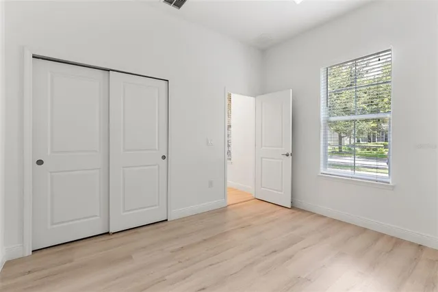 a view of an empty room with wooden floor and a window