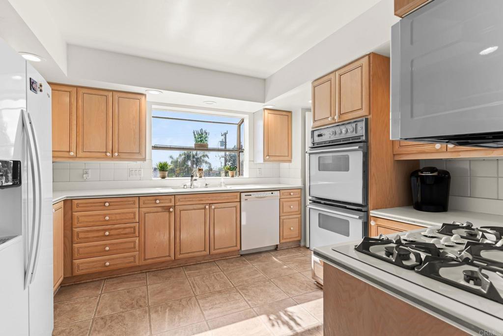 1105 Reed Avenue San Diego, CA 92109 - Photo 16 of 35 a kitchen with stainless steel appliances kitchen island granite countertop a stove and a refrigerator