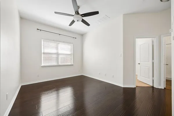 an empty room with wooden floor fan and windows