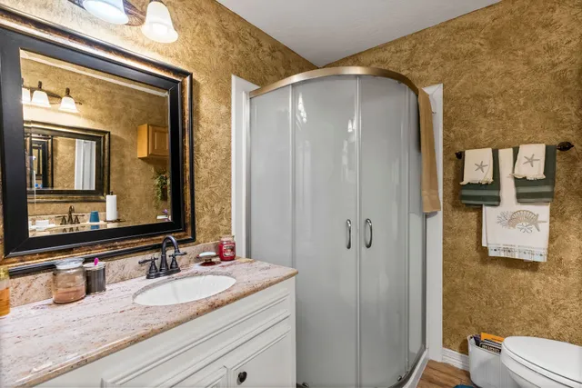 a bathroom with a granite countertop sink toilet and shower