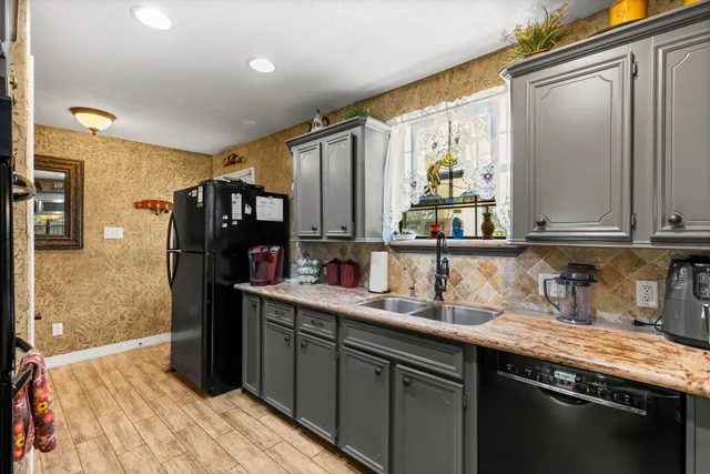 a kitchen with stainless steel appliances granite countertop a sink refrigerator and cabinets